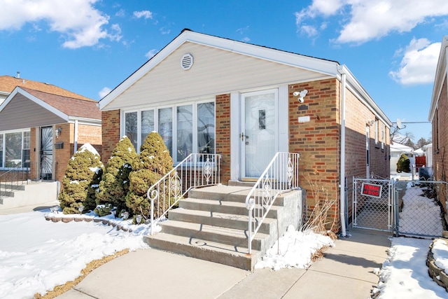 view of front of home with a gate, brick siding, and fence