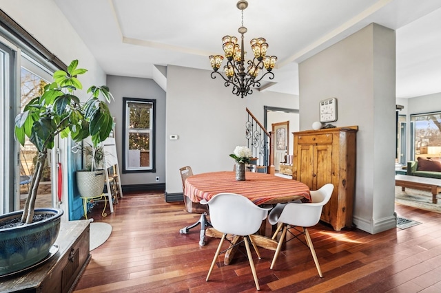 dining room featuring dark wood-style floors, a chandelier, baseboards, and stairs