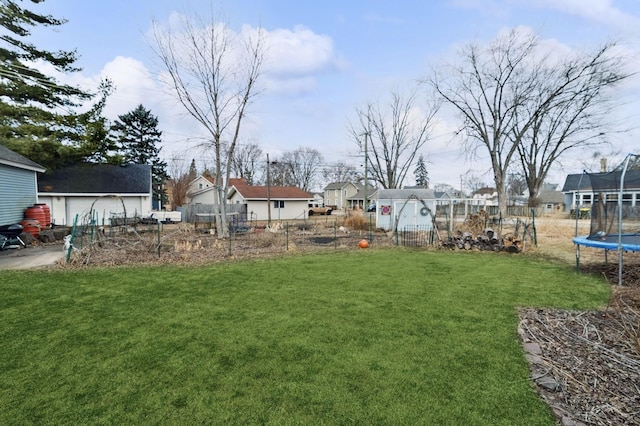 view of yard featuring a trampoline, fence, and a residential view