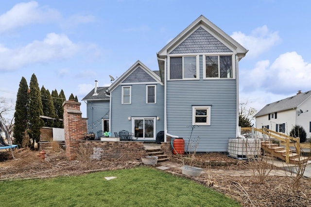 rear view of house with a trampoline, a lawn, and a patio