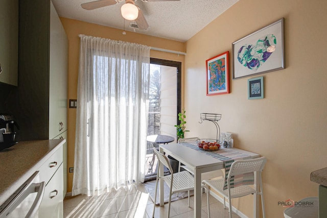 dining space with a ceiling fan, light tile patterned flooring, and a textured ceiling