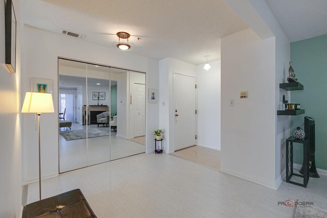 interior space with visible vents, a textured ceiling, and baseboards