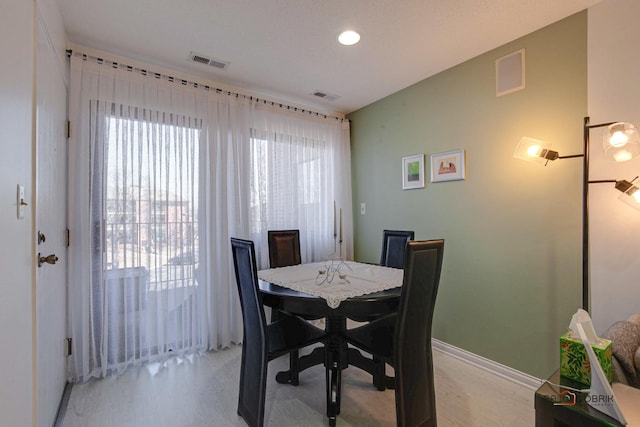 dining space with light wood-type flooring, visible vents, and baseboards