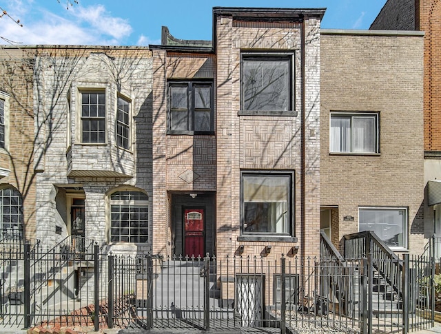 multi unit property featuring brick siding and a fenced front yard