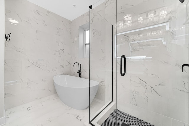 bathroom with stone wall, a marble finish shower, marble finish floor, and a freestanding bath