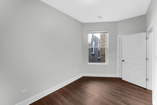 unfurnished bedroom with visible vents, dark wood finished floors, and baseboards