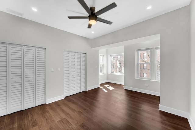 unfurnished bedroom with recessed lighting, wood finished floors, visible vents, baseboards, and multiple closets