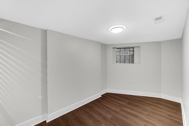 below grade area with dark wood-style floors, visible vents, and baseboards