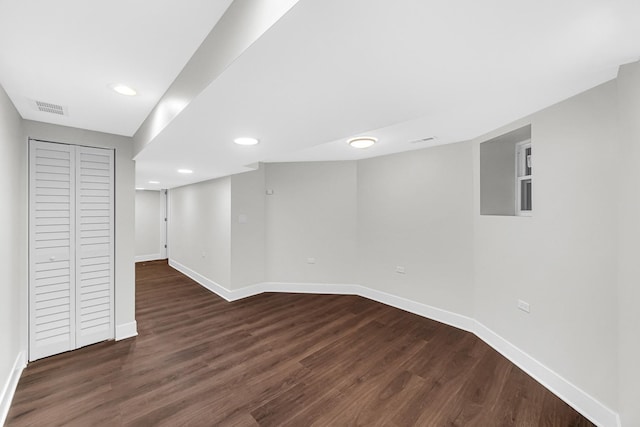 finished basement featuring dark wood-type flooring, recessed lighting, visible vents, and baseboards