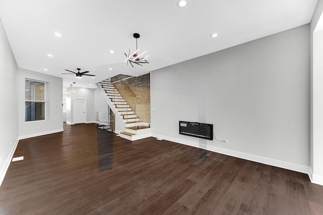 unfurnished living room with baseboards, dark wood finished floors, a glass covered fireplace, stairway, and recessed lighting