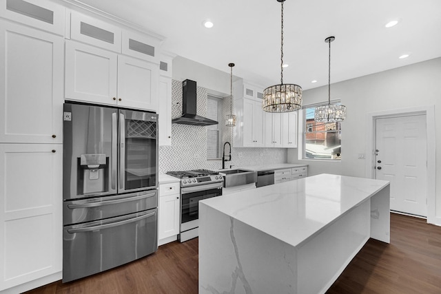 kitchen with stainless steel appliances, a sink, a center island, wall chimney exhaust hood, and glass insert cabinets