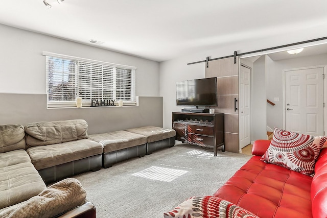 carpeted living area featuring a barn door and visible vents