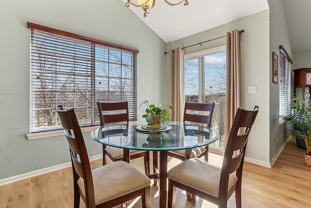 dining space with light wood-style floors, baseboards, and vaulted ceiling