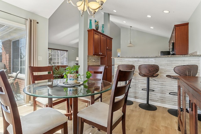 dining area with lofted ceiling, an inviting chandelier, light wood-style flooring, and recessed lighting