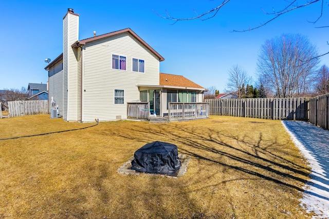 back of property with central air condition unit, a lawn, a fenced backyard, a sunroom, and a chimney