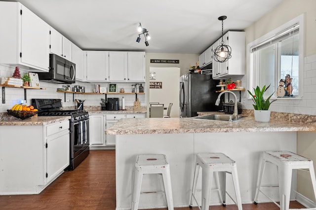 kitchen featuring black appliances, white cabinets, a peninsula, and a sink