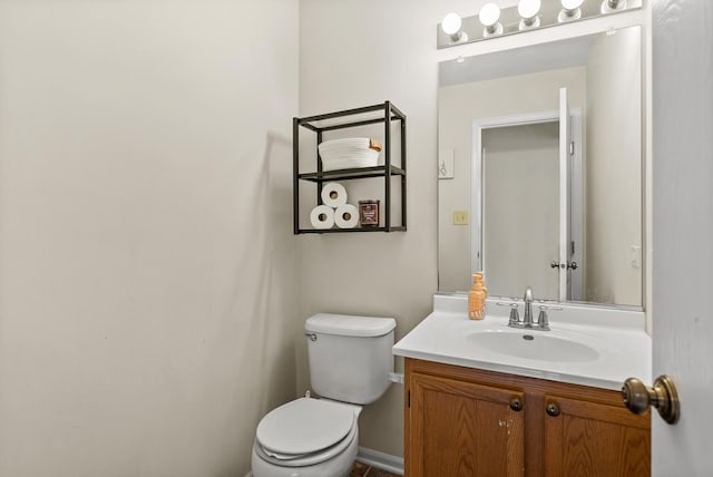 half bath with baseboards, toilet, and vanity