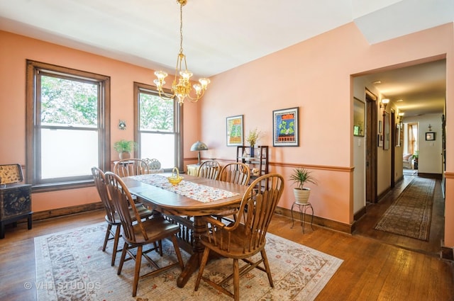 dining space with hardwood / wood-style flooring, baseboards, and an inviting chandelier