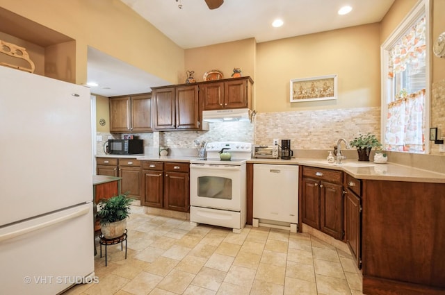 kitchen with tasteful backsplash, light countertops, a sink, white appliances, and under cabinet range hood