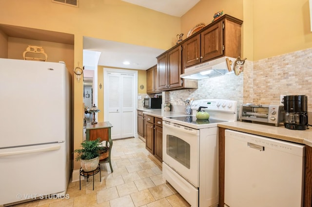 kitchen featuring visible vents, light countertops, backsplash, white appliances, and under cabinet range hood