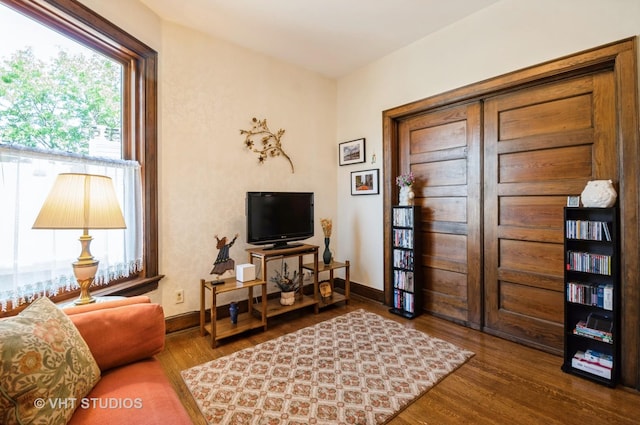 living area with a healthy amount of sunlight, baseboards, and wood finished floors