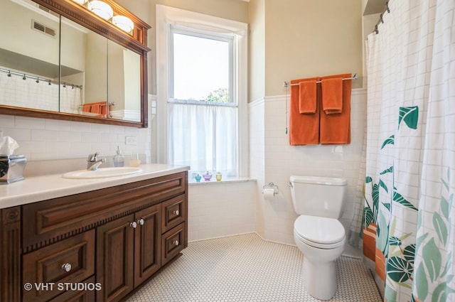 bathroom featuring visible vents, toilet, curtained shower, vanity, and tile walls