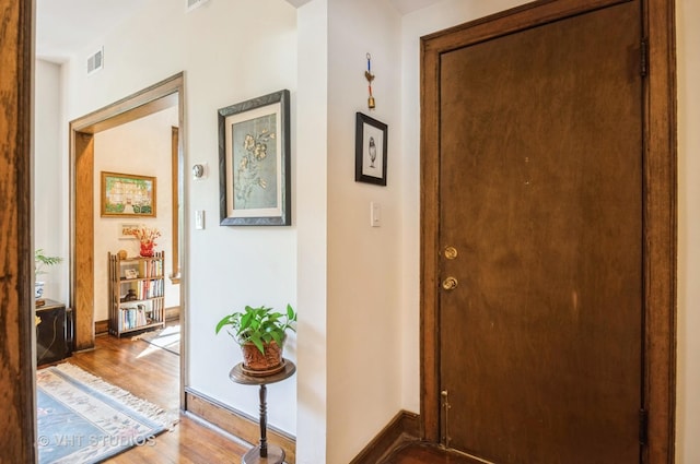 interior space with baseboards, visible vents, and wood finished floors