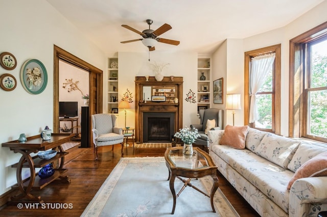 living area featuring built in shelves, a healthy amount of sunlight, and wood finished floors