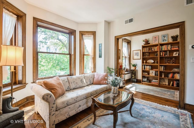 living room with baseboards, visible vents, and wood finished floors