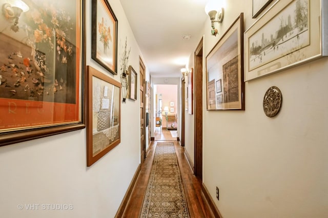 hallway with dark wood-style flooring and baseboards