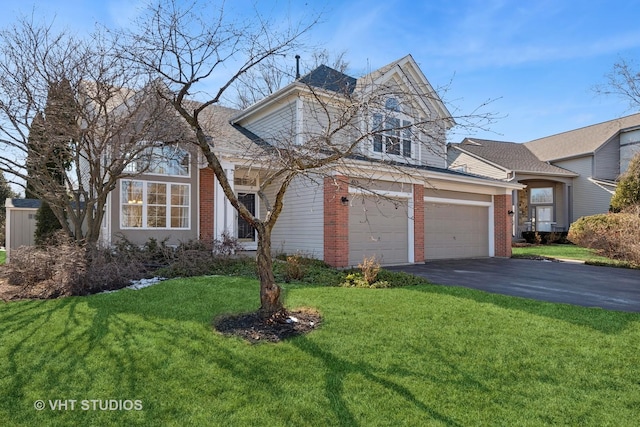 traditional-style house featuring aphalt driveway, a front yard, and brick siding