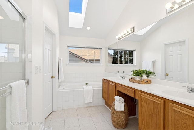 bathroom with a garden tub, vaulted ceiling with skylight, a sink, and tile patterned floors