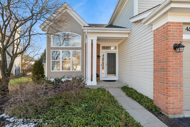 entrance to property featuring a garage and brick siding