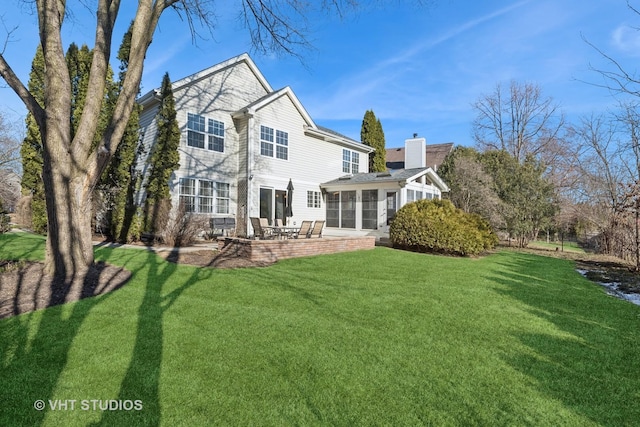 rear view of house with a sunroom, a lawn, and a patio