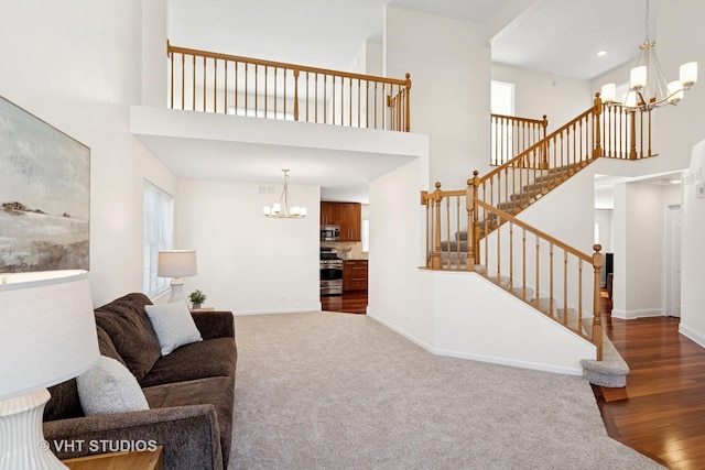 living room with baseboards, wood finished floors, a high ceiling, stairs, and a notable chandelier