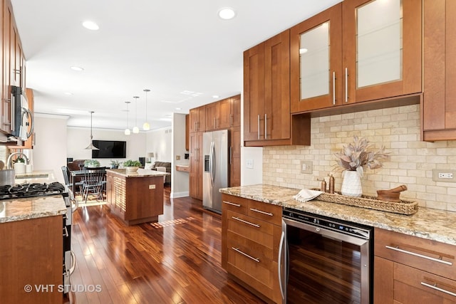 kitchen with open floor plan, wine cooler, brown cabinetry, and appliances with stainless steel finishes