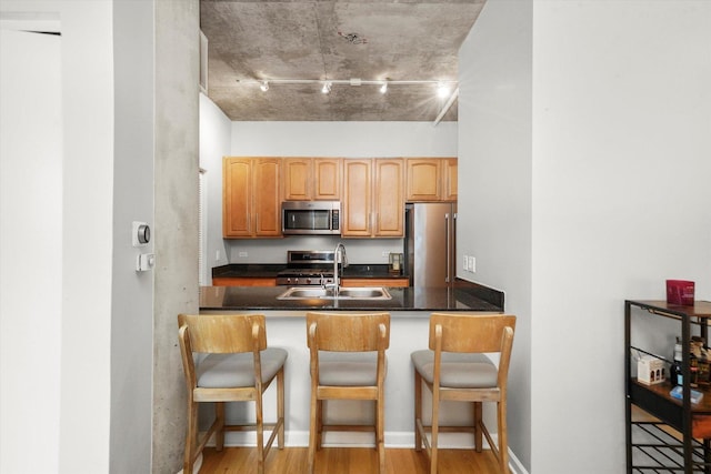 kitchen with appliances with stainless steel finishes, dark countertops, a sink, and a kitchen breakfast bar