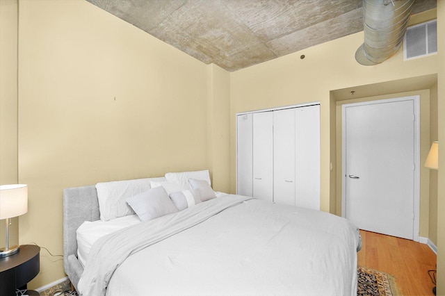 bedroom featuring light wood-type flooring, a closet, and visible vents