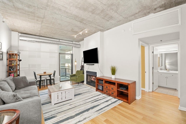 living room with a warm lit fireplace, wood finished floors, and baseboards