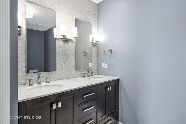 bathroom with a sink, backsplash, double vanity, and toilet