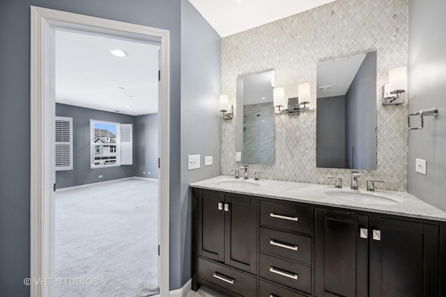 bathroom with decorative backsplash, baseboards, a shower with door, and a sink