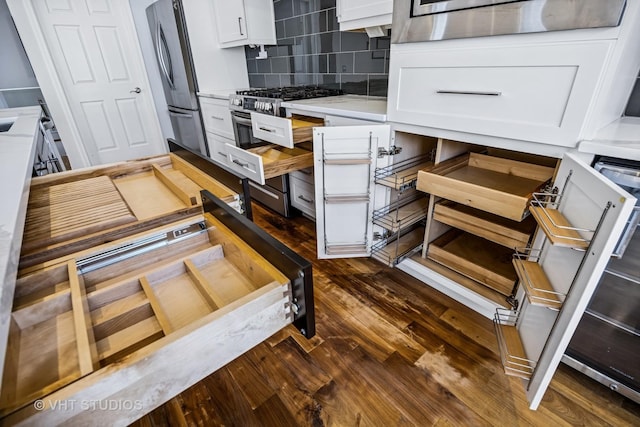 kitchen with dark wood finished floors, stainless steel appliances, light countertops, white cabinets, and tasteful backsplash