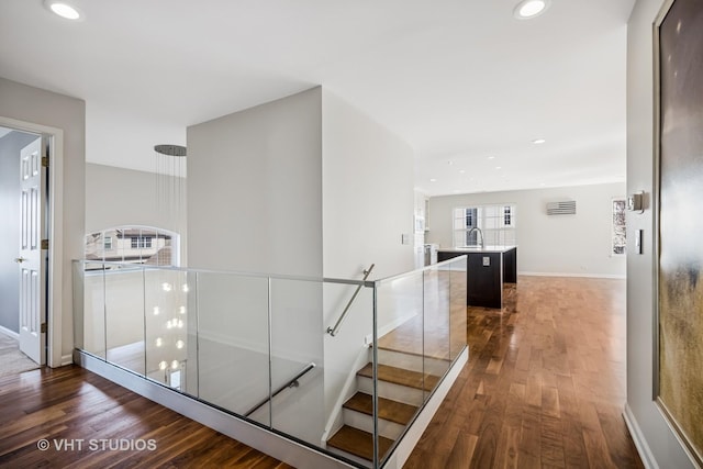 staircase with recessed lighting, baseboards, wood finished floors, and a wall unit AC