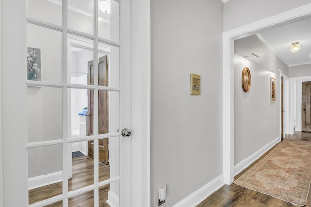 hall with ornamental molding, baseboards, and wood finished floors