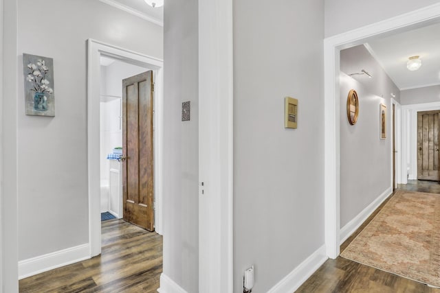 corridor with crown molding, dark wood-type flooring, and baseboards