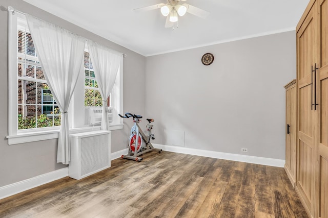 workout room featuring radiator, ceiling fan, baseboards, and wood finished floors