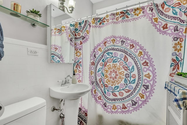 full bath with wainscoting, tile walls, and toilet