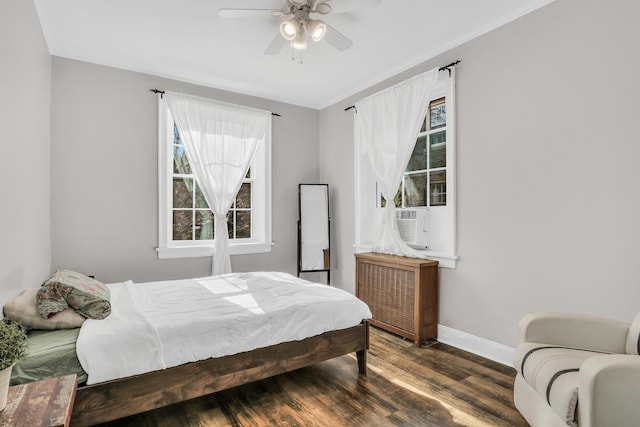 bedroom featuring radiator heating unit, ceiling fan, wood finished floors, cooling unit, and baseboards