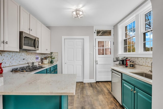 kitchen with tasteful backsplash, appliances with stainless steel finishes, dark wood-type flooring, white cabinetry, and a sink