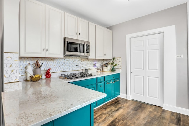 kitchen with blue cabinets, white cabinetry, appliances with stainless steel finishes, dark wood-style floors, and tasteful backsplash